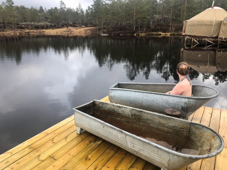Kvinne nyter et varmt bad i eldre sink-badekar ute på brygga hos Canvas Telemark