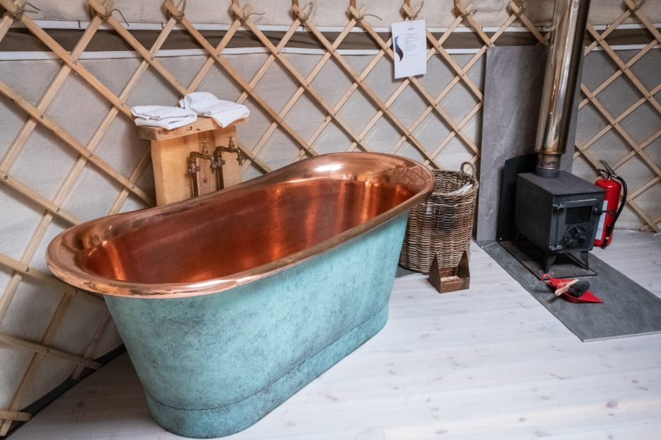 the inside of a luxury yurt at canvas hove with a bath tub and fireplace