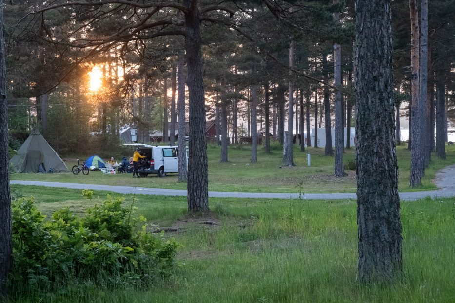 Solnedgang over Canvas Hove hvor man ser et telt, en sykkel og en varebil