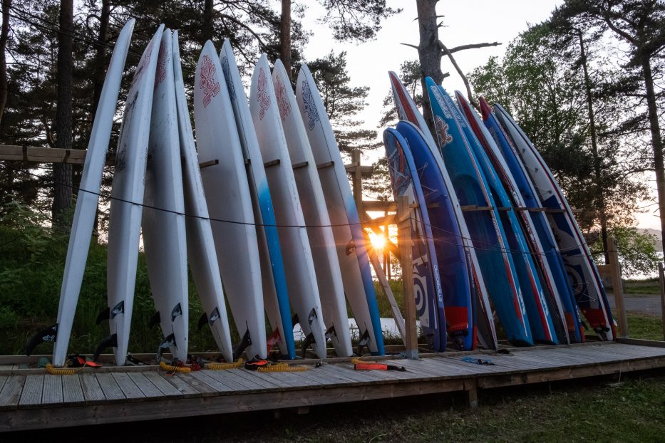 the sun shining between standing surf boards at canvas hove