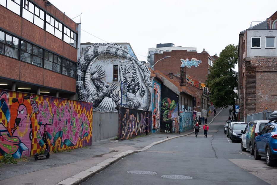 To personer går i gata utenfor området ved Blå i Oslo med myte gatekunst og grafitti på veggene rundt de