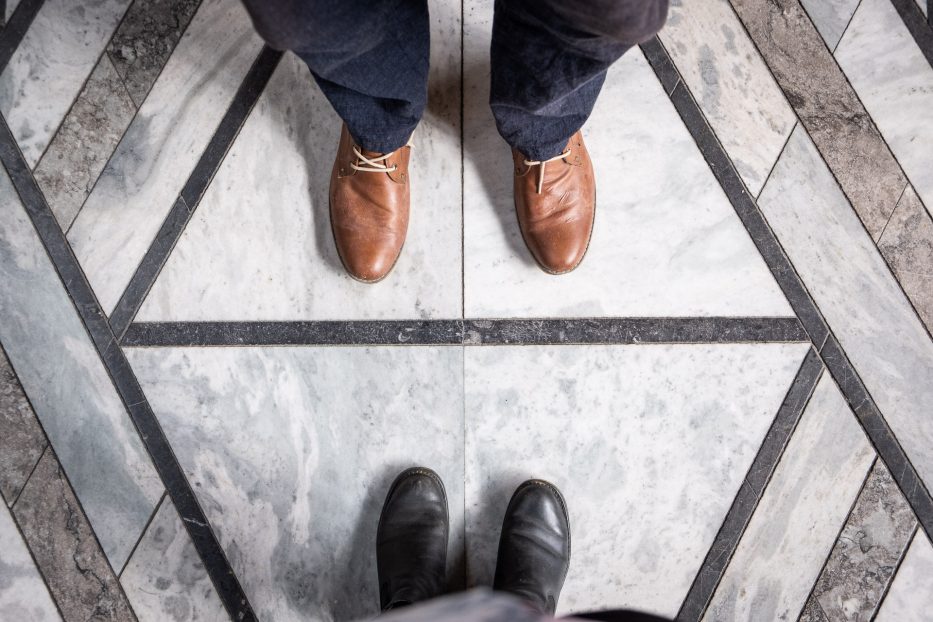 two pair of feet with brown and black boots