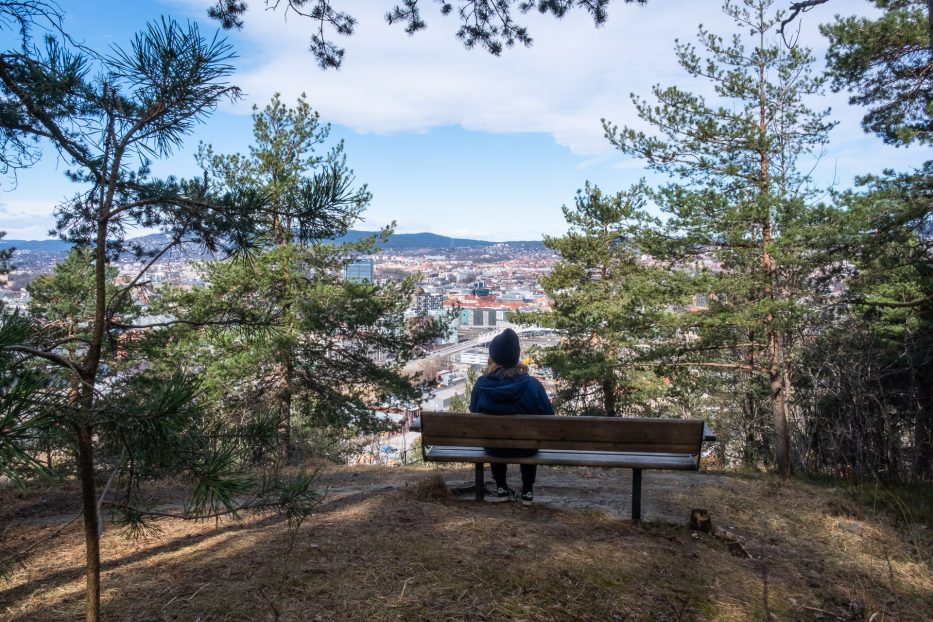 person sitter i Ekebergparken og ser utover oslo