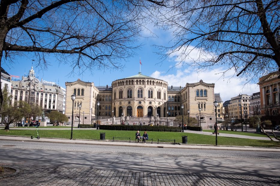 stortinget in oslo with two people sitting in front on a bench