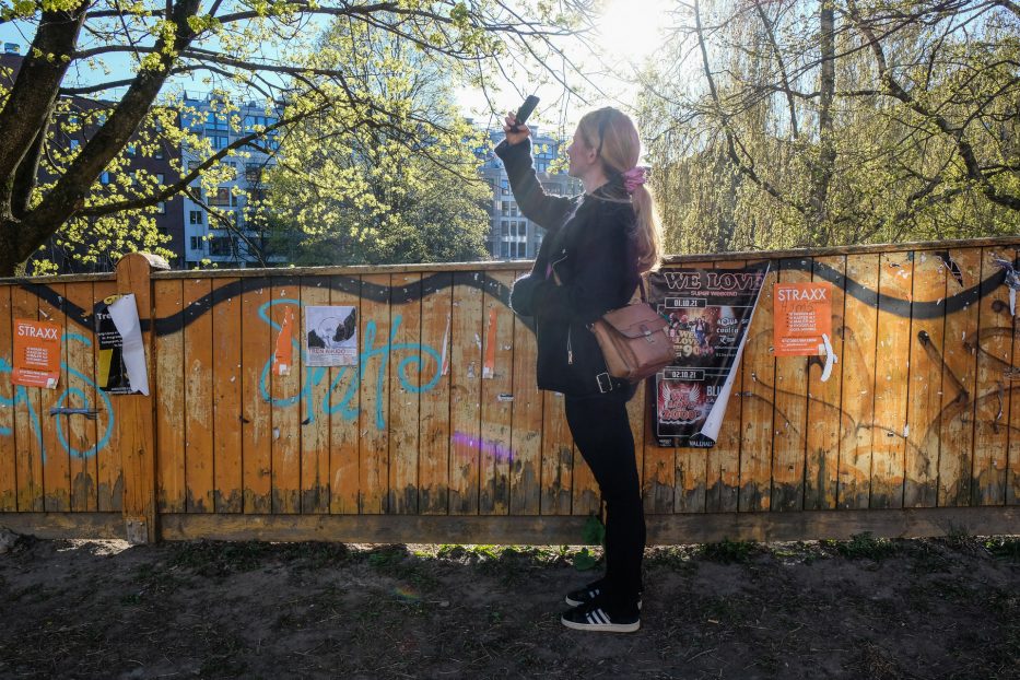 kvinne fotograferer et tre med smarttelefon