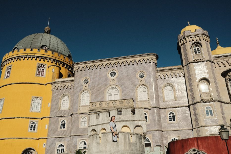 en kvinne står utenfor fargerike Pena palace i sintra