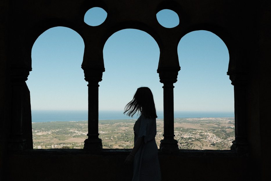 silhuetten av enn kvinne og en bygning med sintra i bakgrunnen