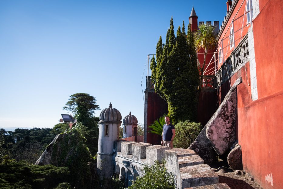 man standing between colorful buildings at Pena Palace in Sintra portugal