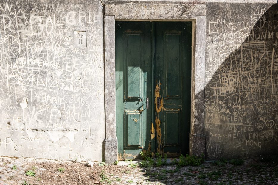 an old door on a building where people have carved in messages on the wall around it