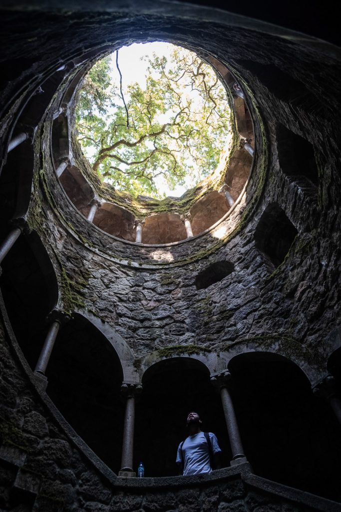 man standing down in the Initiation well at Quinta da Regaleira in sintra looking up