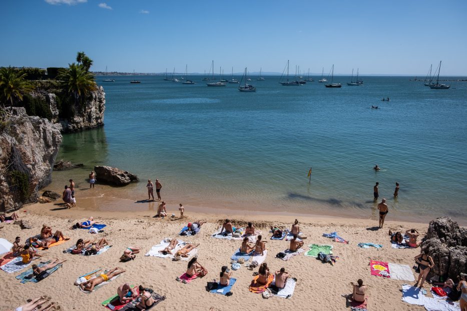 strand med en rekke mennesker på og seilbåter utenfor