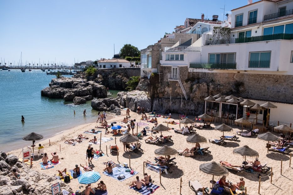 strand fylt med mennesker og parasoller i cascais