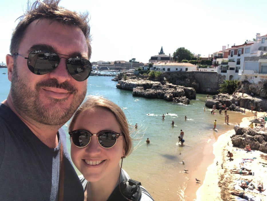 mann og kvinne tar selfie foran strand i cascais