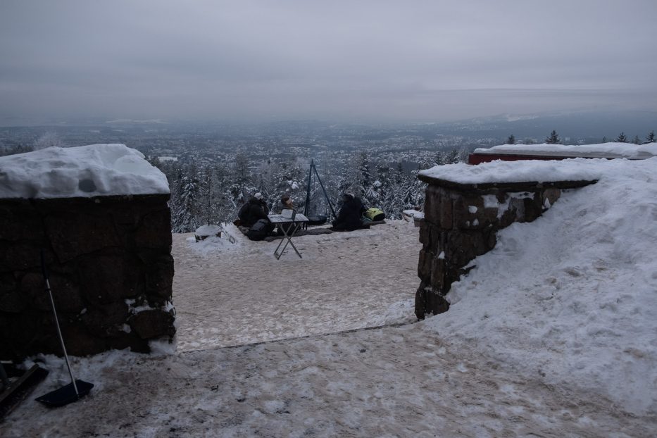 mennesker samlet rundt en bålpanne på Grefsenkollen med utsikt utover oslo i bakgrunnen