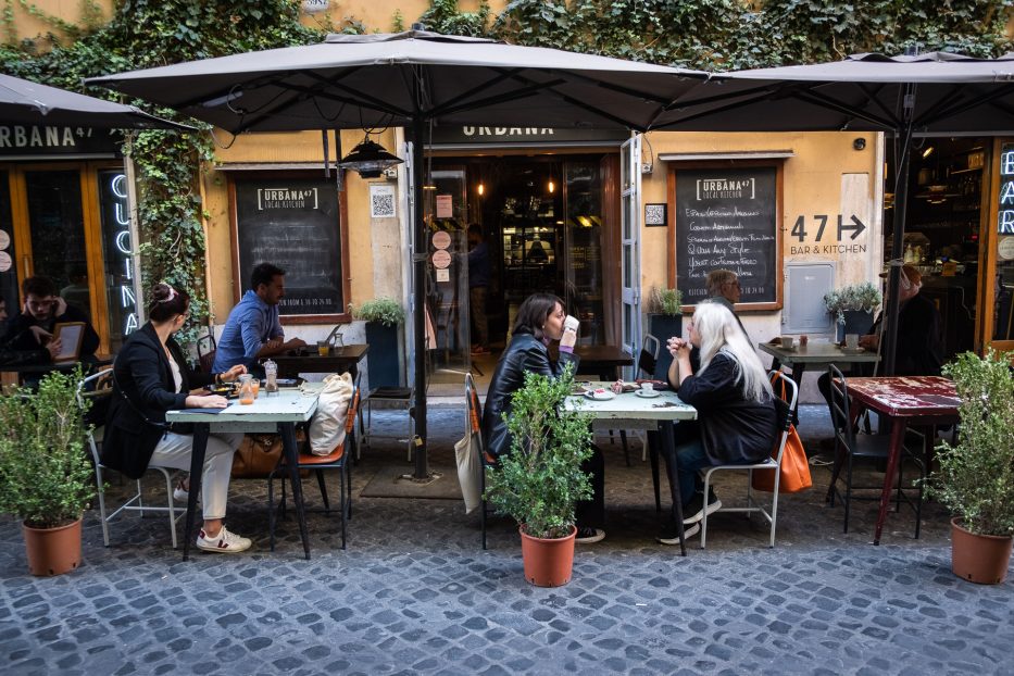 people eating outside on a street cafe in rome
