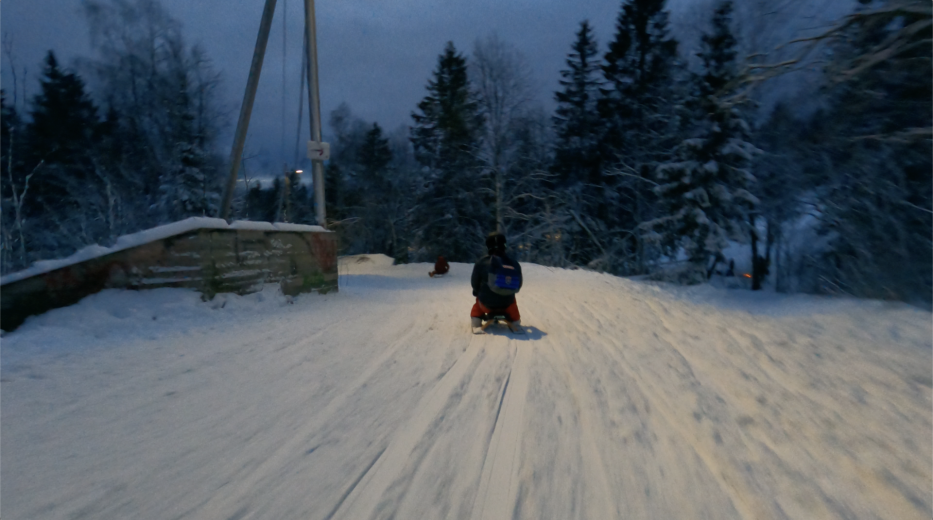 the back of a man with helmet on a sledge going down korketrekkeren in oslo