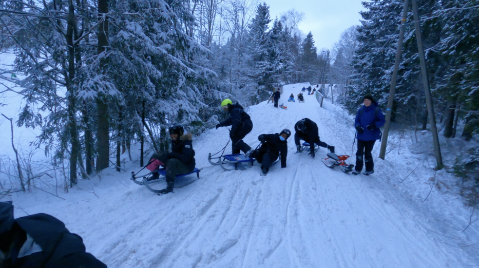 people sledging down korketrekkeren in norway covered in snow