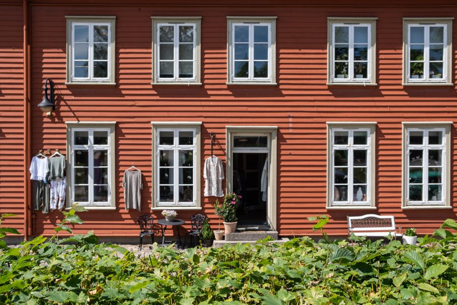 a red house with clothes hanging outside and a green hedge