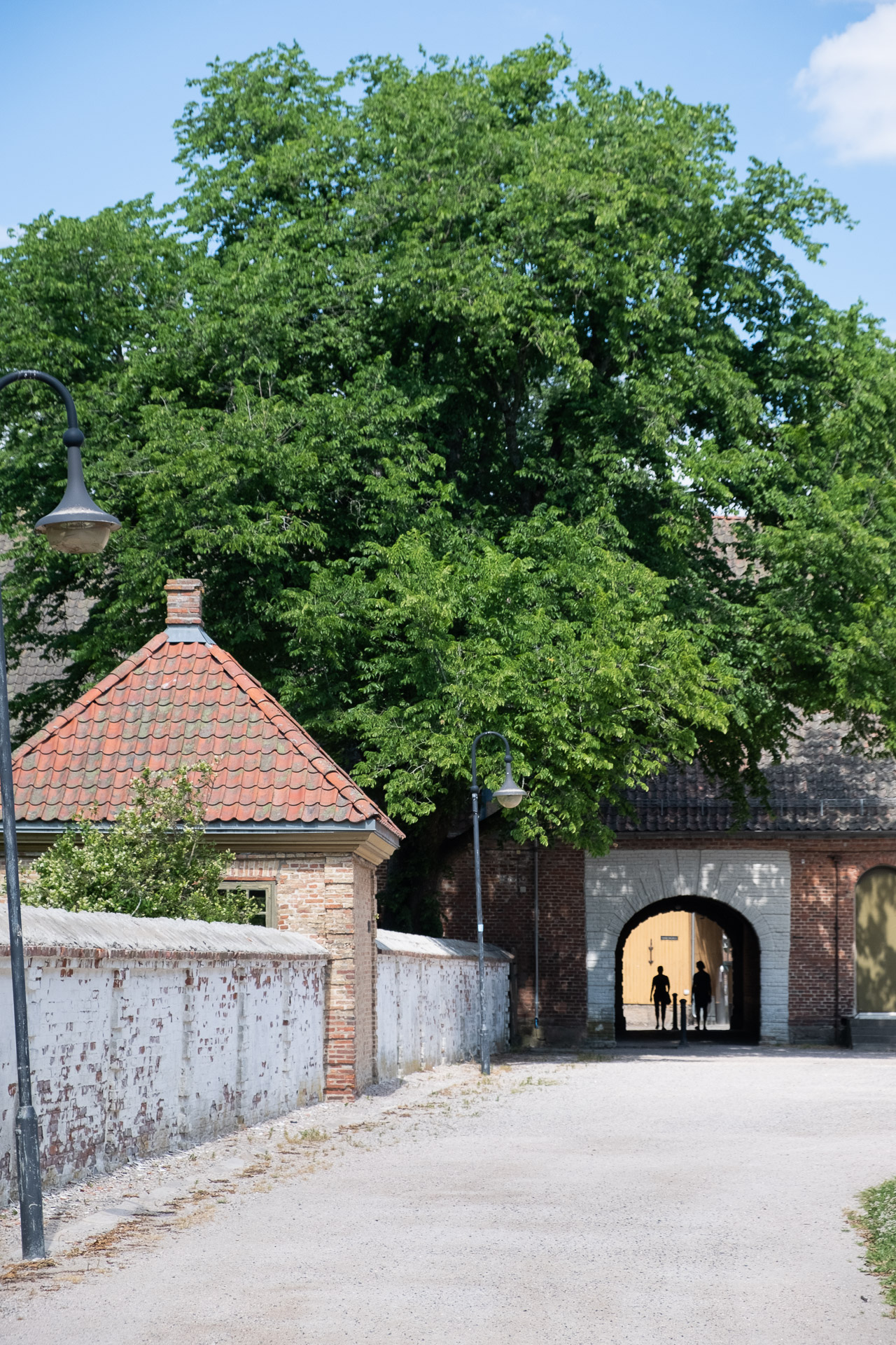 man and woman walking through an arch in the old town of fredrikstad