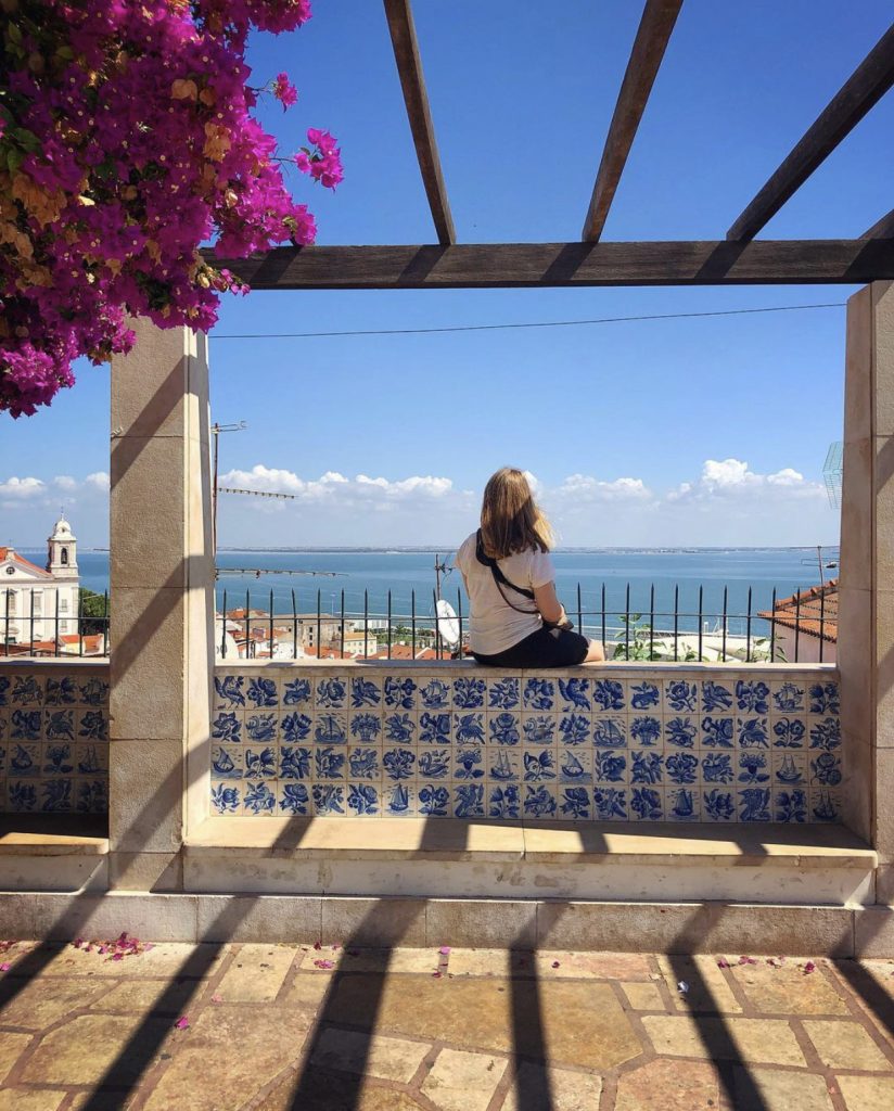 kvinne ser utover byen og havet fra et utsiktspunkt i lisboa