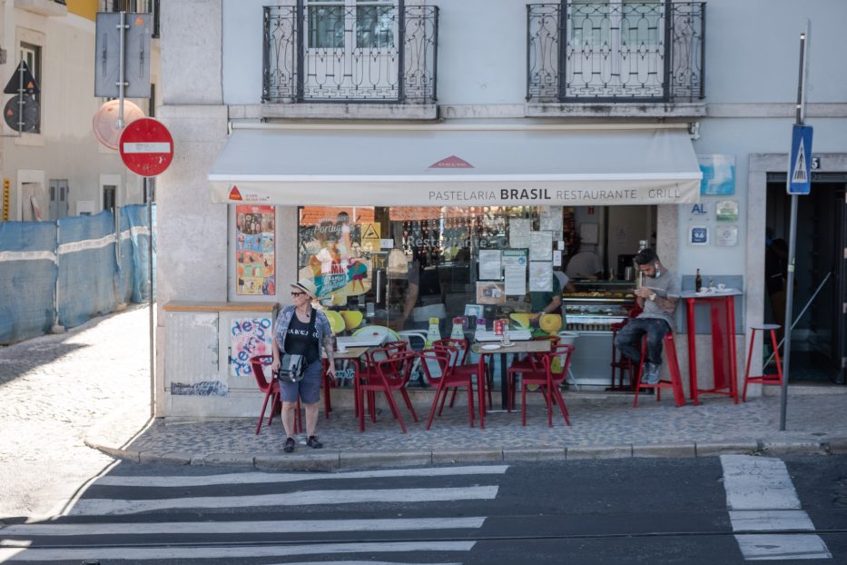 woman waiting to cross the road and man sitting in a cafe