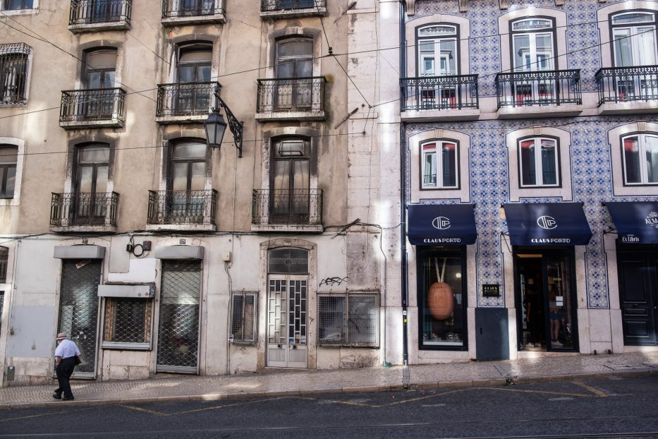 en gammel mann med hatt går nedover en gate i Bairro Alto