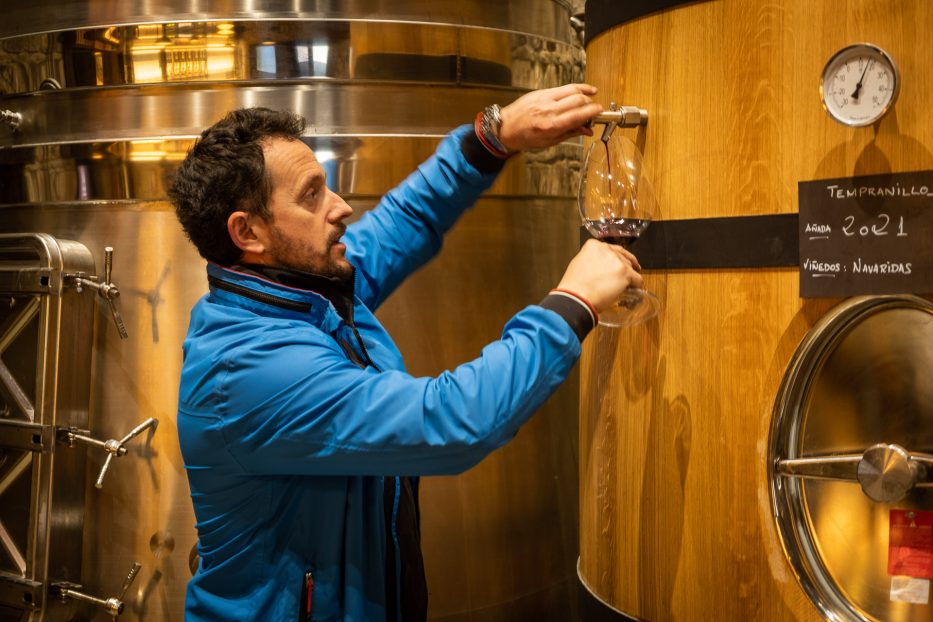 man pouring wine out of a wine barrel