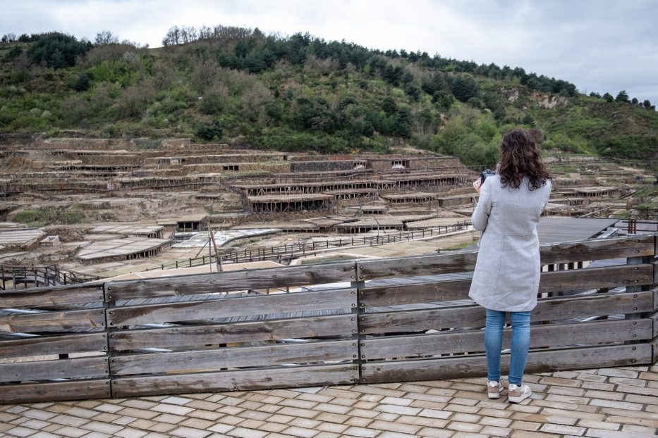 woman in grey coat looking out over Salinas de anana