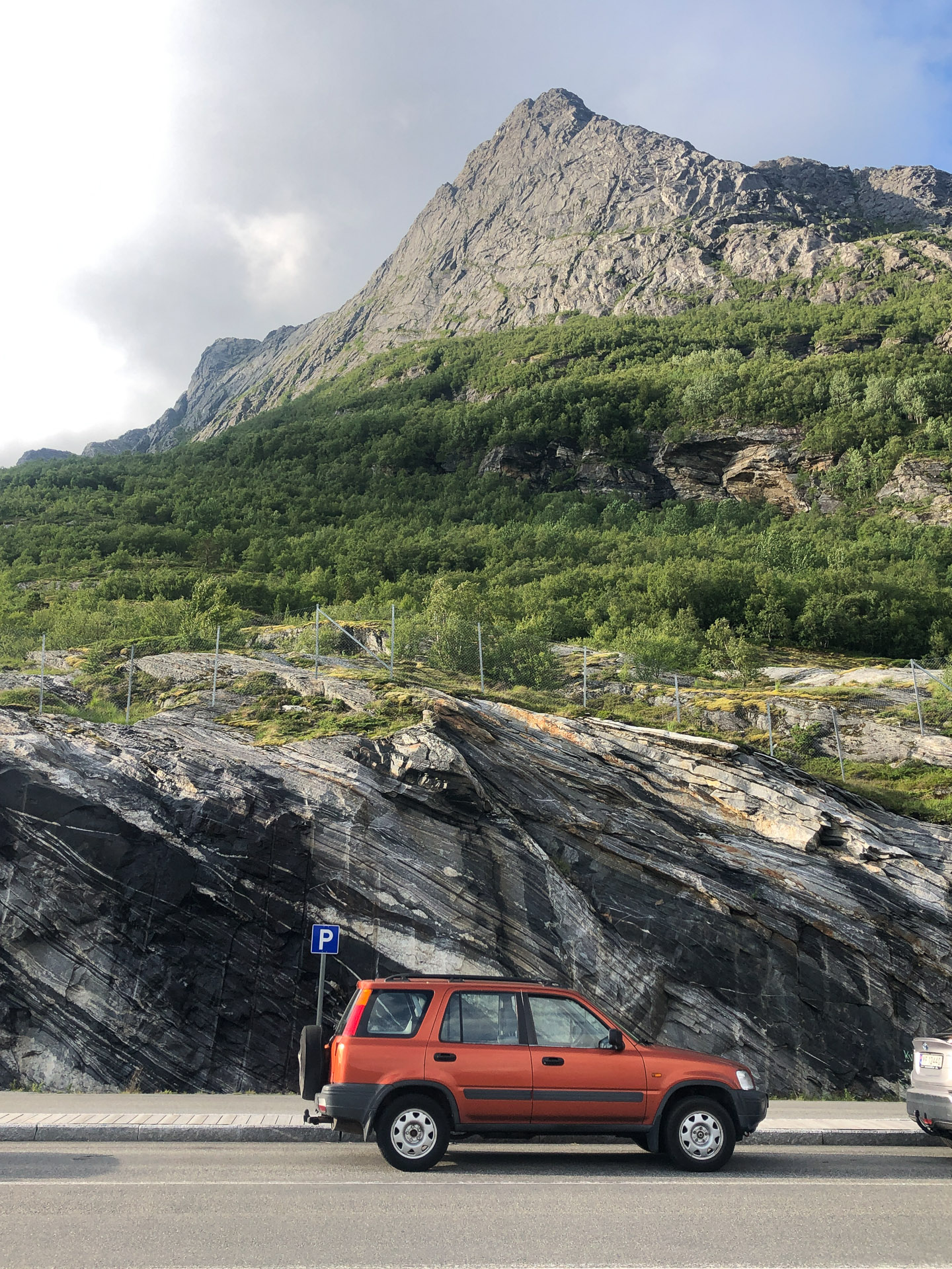 orange car in front of a steep mountain