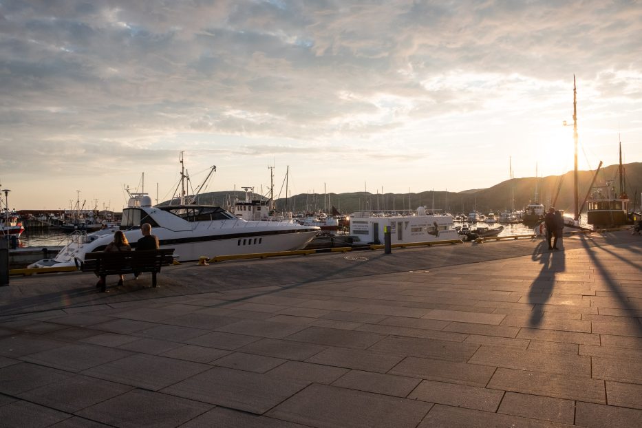 sol over Bodø havn med båter og mennesker