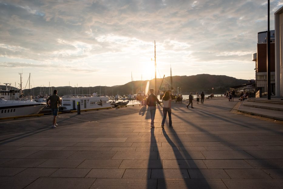 people walking in the sun on the harbor in Bodø