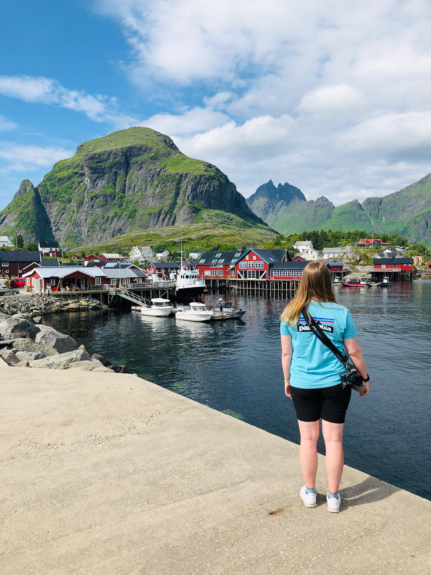 kvinne i turkis t-skjorte med ryggen til ser utover å i lofoten