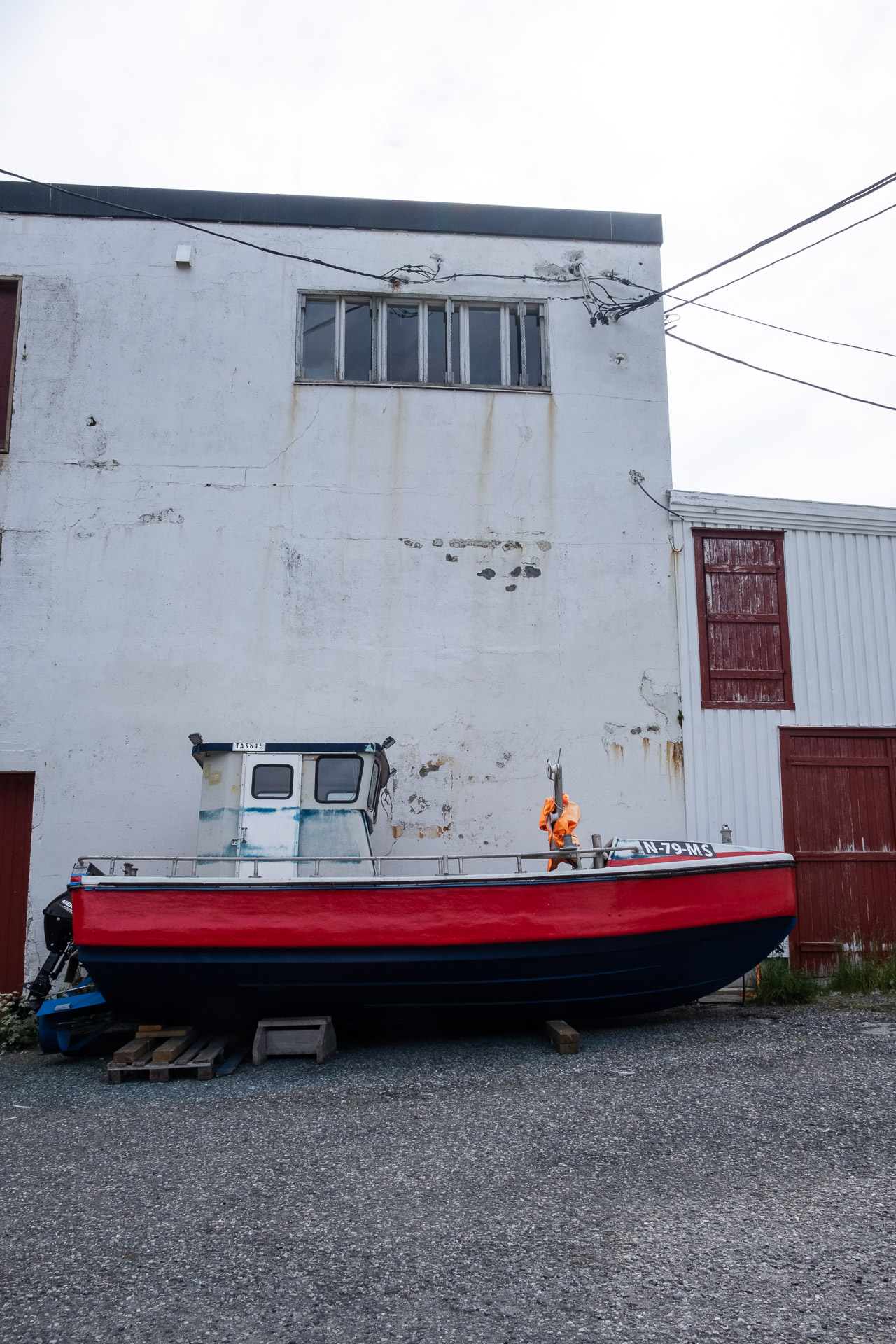 a fishing boat on land in front of an old wall