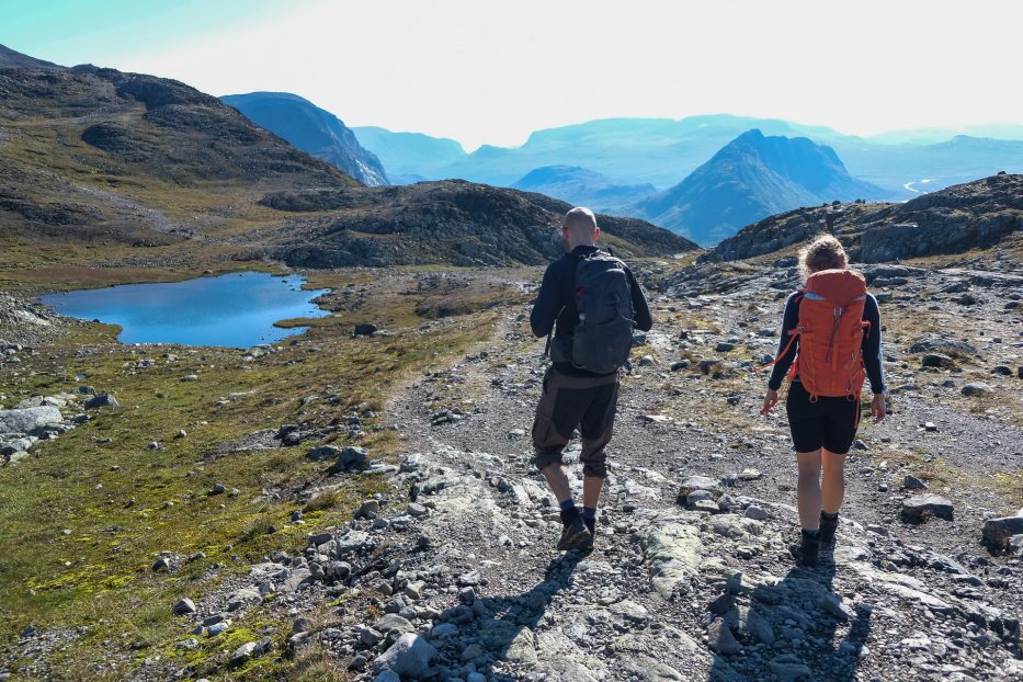 man and woman with backpacks hiking on a sunny day