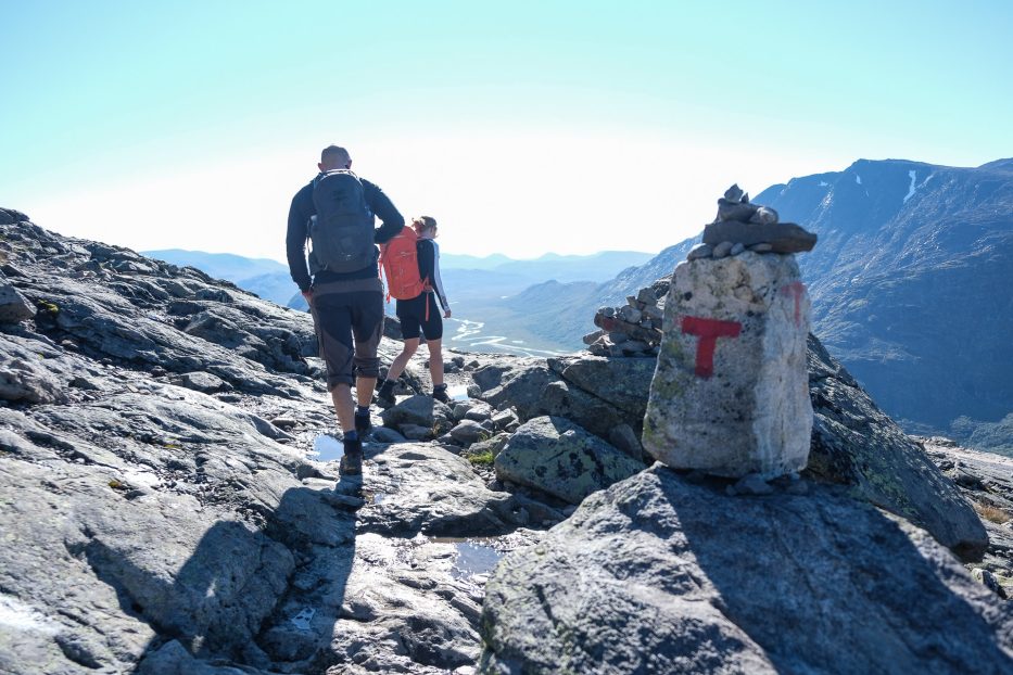 mann og kvinne går tur i fjellet og en stein med rød t malt på