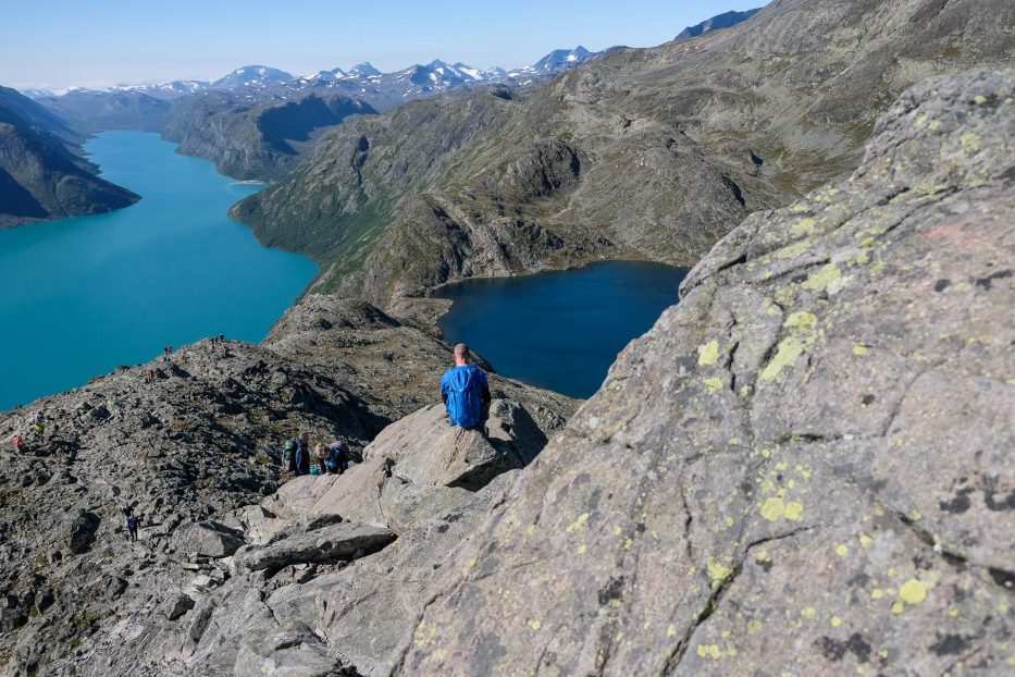 man sitting at besseggen looking out over the majestic mountain and fjord view in norway