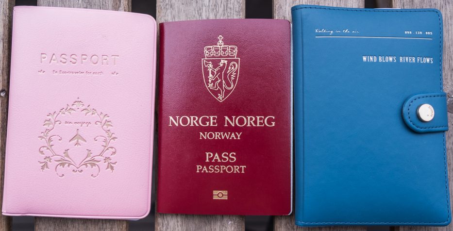 et rosa og et blått passfutteral med et rødt norsk pass i midten