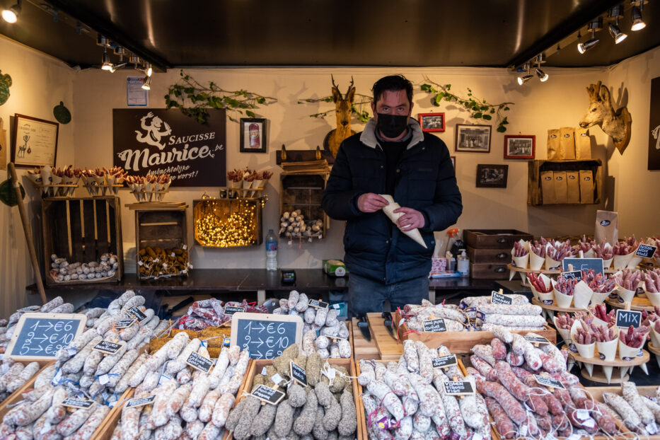 man selling sausages at a stand at the christmas market in bruges