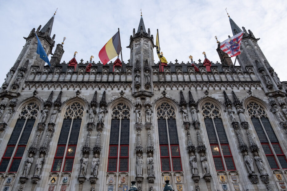 grand building with several flags outside in bruges belgium