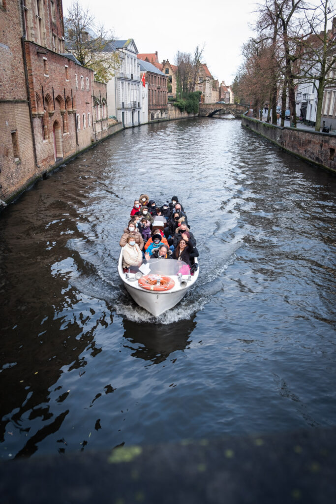 boat filled with people in the canal of bruges
