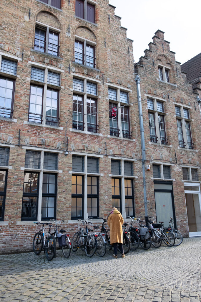 person leaning over a row of bikes in front of a stone house 