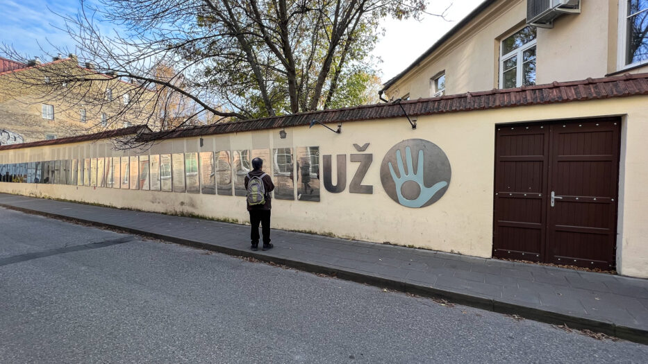 en mann står foran grunnlovene som henger på en vegg i uzupis vilnius litauen