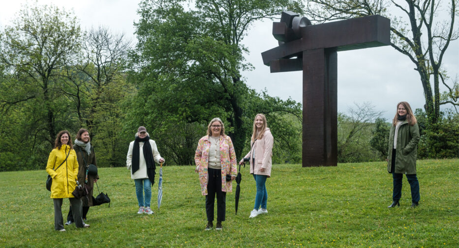 six women standing in front of a statue at chillida leku in spain