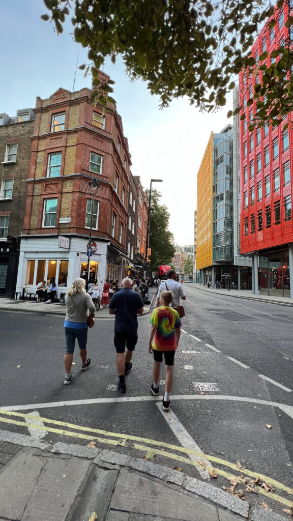 fire mennesker i sommerlige klær går med ryggen mot kamera i fargerik gate i london