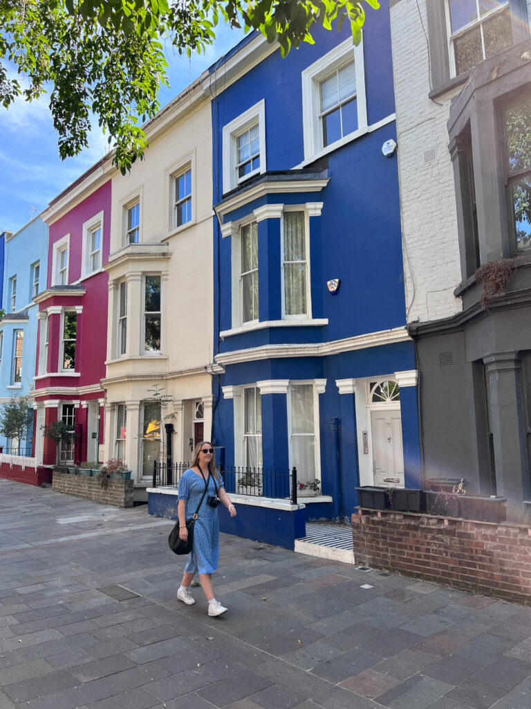 woman in blue dress walking past colourful houses in notting hill