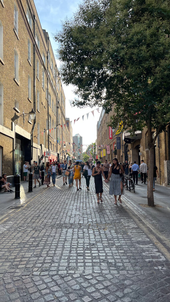 people walking in a sunny green summer street in london
