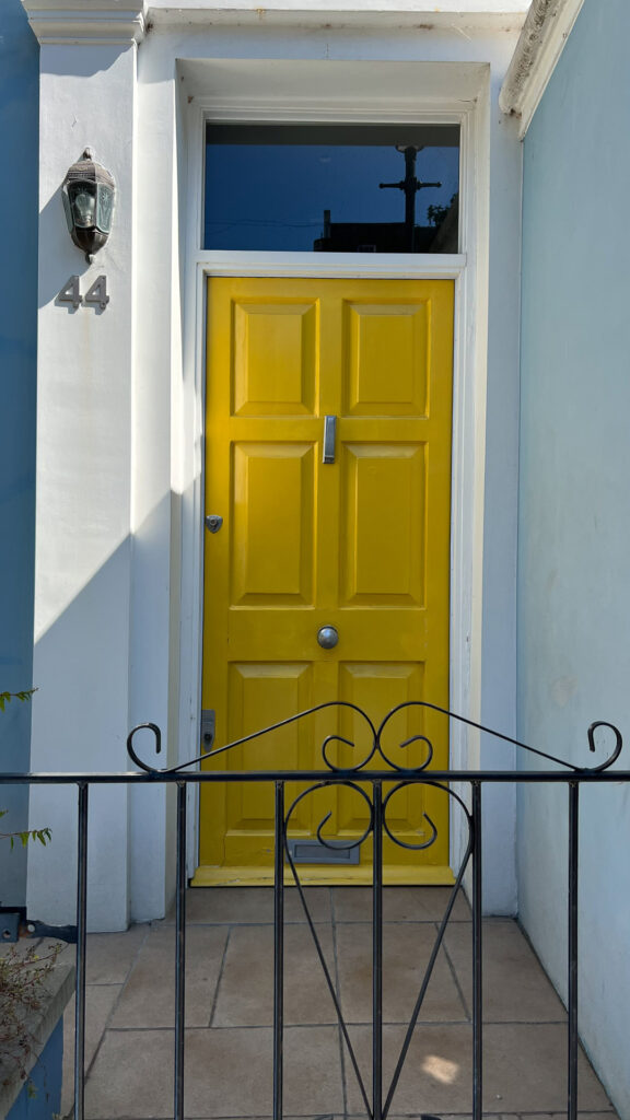 bright yellow door on a pastel blue house in notting hill