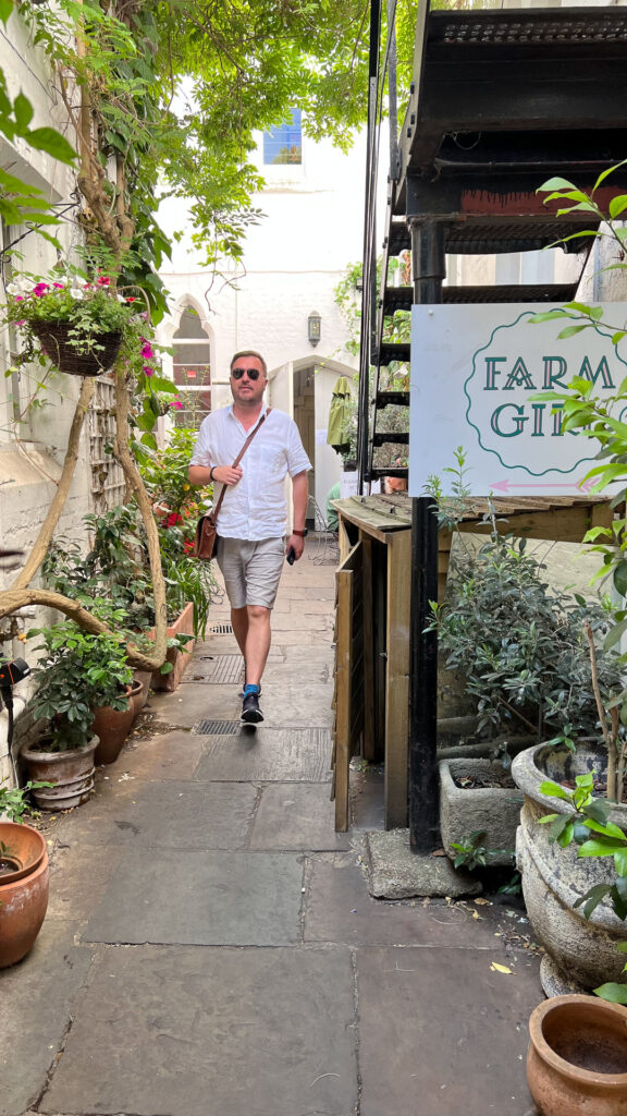 man walking into a shop with flowers outside in london