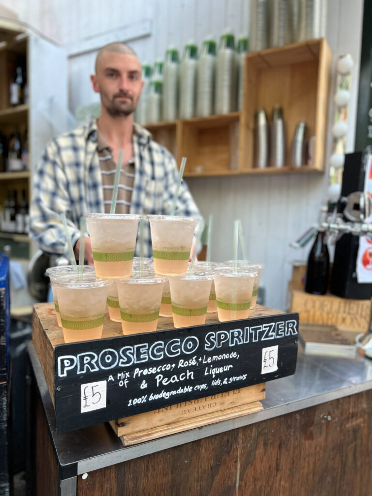 man selling prosecco spritzers at borough market in london