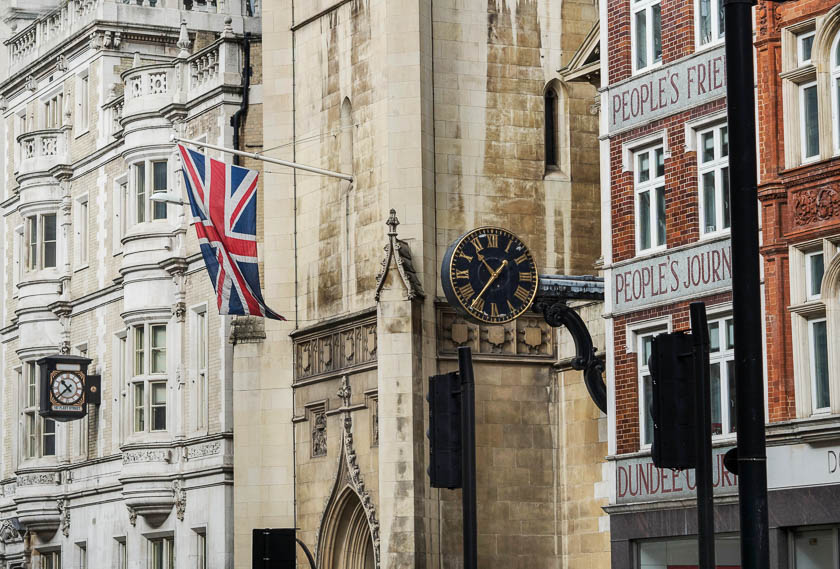 tre ulike husfasader med to klokker og det britiske flagget hengende